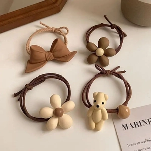 Set of four brown and cream hair ties featuring bow, flower, and bear charms
