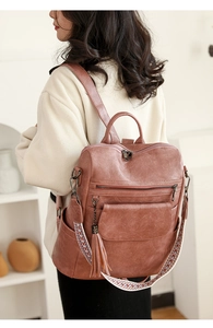 Detail of pink-brown faux leather backpack with colorful woven strap and tassel charm