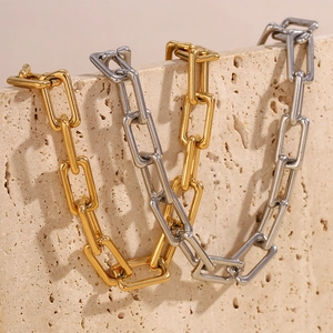 Detail of square link chain necklace in gold and silver finish on stone background