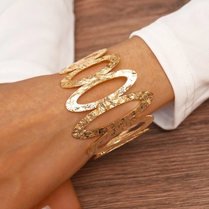 Detailed view of wide gold-plated hammered cuff bracelet featuring unique wavy texture
