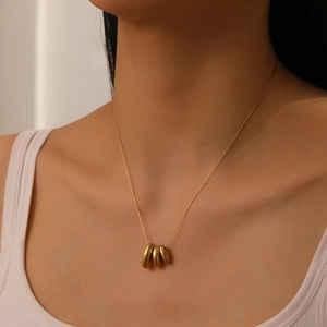 Détail de trois pendentifs dorés en forme de larme sur un collier à chaîne pour femme