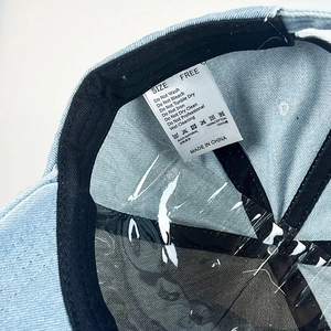 Detail der hellblauen Jeans-Baseballkappe innen mit 100% Baumwolletikett und Schweißband