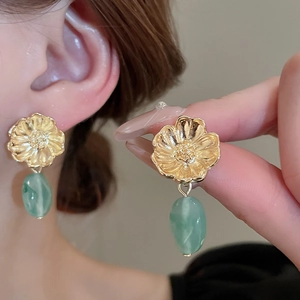 Vintage gold flower earrings with light green teardrop resin beads on model