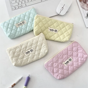Close-up of quilted cosmetic bags in pastel mint, yellow, white, and purple colors