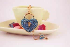 Detail of a gold heart lock and key keychain with blue rhinestones on a ceramic cup