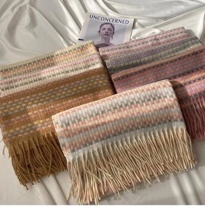 Close-up of multicolored plaid scarves with fringe details on white silk background
