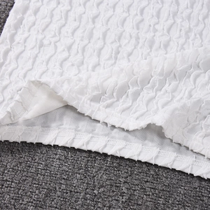 Détail du tissu blanc gaufré et des coutures de finition de qualité sur la robe sexy