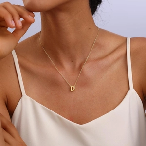 Close-up of a 3D bubble letter D pendant necklace in gold plating on female model
