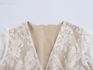 Detailed close-up of white lace V-neck cardigan featuring intricate floral patterns and S tag