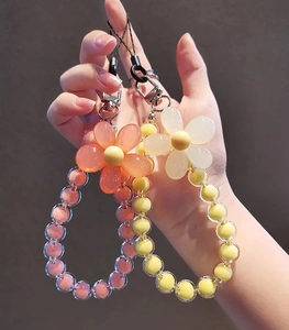 Close-up of handmade macaron beaded phone charms with flowers and metal lobster clasps