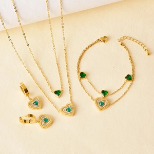 Golden heart jewelry set with green gemstones, including necklace, bracelet and earrings