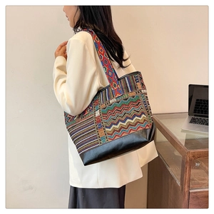 Detailed side view of ethnic canvas tote bag with geometric pattern and black leather base