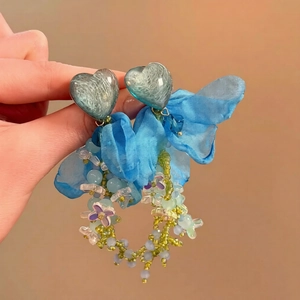Gros plan de boucles d'oreilles cœur bleu avec pampilles florales et nœud en tulle
