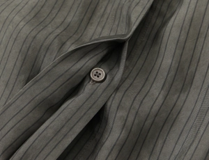 Close-up of dark grey striped shirt fabric showing precise stitching and matching buttons