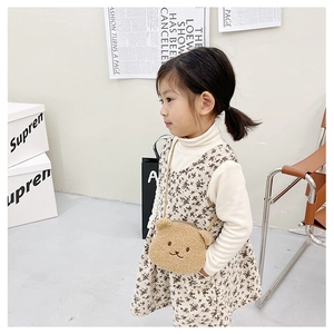 Detail view of a cute brown plush bear crossbody bag worn by a child girl model