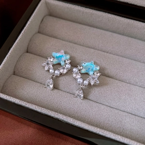 Macro shot of silver star earrings with blue marble stone and pear-shaped zircon
