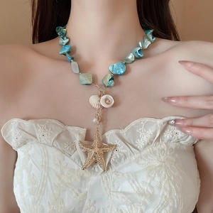 Detail of beach-style necklace with turquoise shells and golden starfish pendant