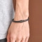 Close-up of a men's black braided leather bracelet with a simple knot closure on a wrist