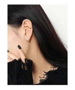 Detail view of layered gold ear cuff and silver geometric textured hoop earring