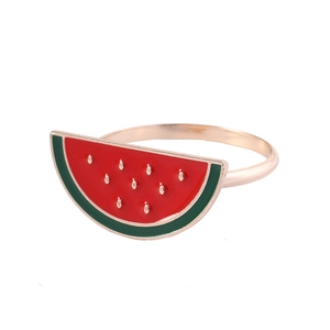 Macro view of watermelon napkin ring with red and green enamel details on gold band