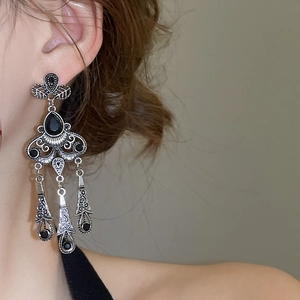 Close-up of vintage silver tassel earrings with black gemstones on a female model