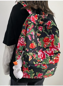 Detail of floral backpack with red and green roses and a white duck plush charm