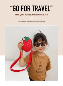 Detail of red strawberry kid bag with gold dots, green leaves and napa leather texture