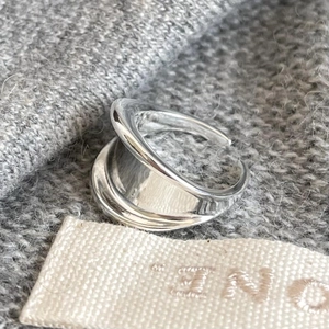 Macro shot of minimalist silver ring with irregular fluid design on soft grey fabric