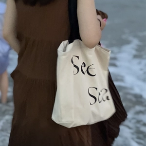 Minimalist off-white canvas tote bag with See Sea print and black straps for women