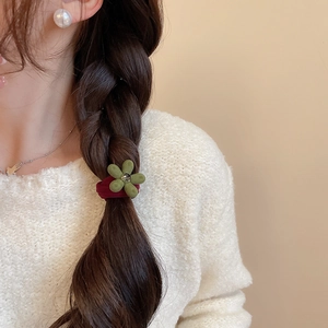 Détail de l'élastique à cheveux fleur verte floquée avec strass sur une tresse