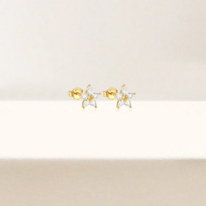 Macro detail of S925 sterling silver stamp and sparkling zircon petals on gold ear studs