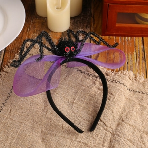 Halloween headband with black plush spider and purple mesh veil on a wooden table