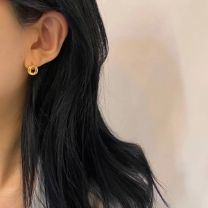 Close-up of minimalist gold-plated donut-shaped hoop earring worn on an earlobe