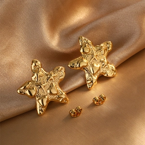 Detail of golden starfish stud earrings with irregular lava texture on gold silk fabric