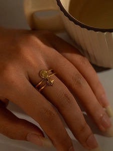 Detail of layered gold titanium ring with sun and star motifs on a model's finger