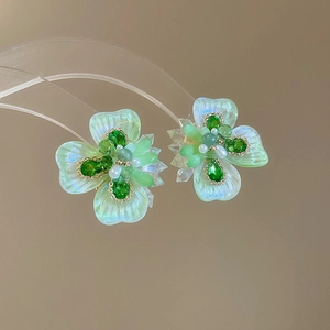 Macro shot of silver needle floral earrings with iridescent green petals and crystals