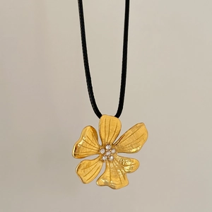 Detailed view of 18k gold floral pendant with brushed texture and micro-set zircons