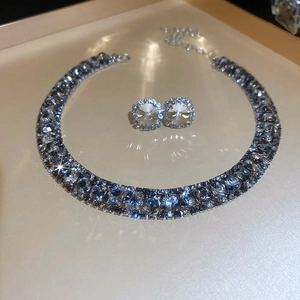 Detailed view of shimmering square zircon necklace and earrings set on a beige background