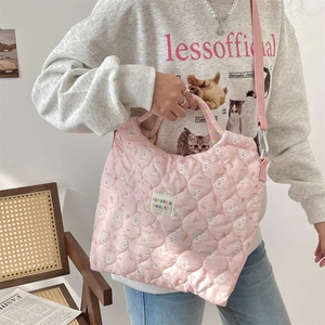 Sac bandoulière matelassé rose avec motifs de lapins et bandoulière sur un mannequin