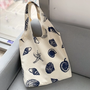 Detail of canvas shoulder bag with blue marine prints resting on a grey sofa