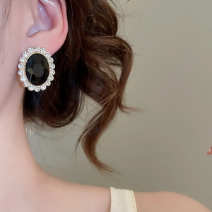 Detail of vintage oval black stone earrings with crystal pavé and golden finish