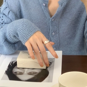 Polished silver wide band ring worn on index finger with a minimalist mirror finish