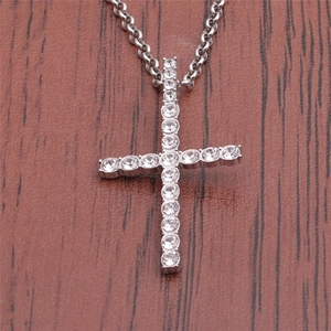 Silver stainless steel cross necklace with rhinestones on a rustic wood background