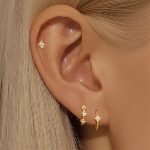 Close-up of gold-plated rhomboid earrings set with sparkling white zircon stones