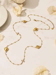Detail van gouden gelaagde ketting met hartjes, zirkoonkruisen en kralenketting op marmer