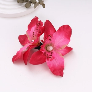 Detail view of pink cymbidium orchid hair clip with realistic speckled petals on surface