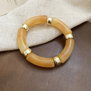 Detailed shot of amber acrylic resin bangle with gold metallic beads on fabric