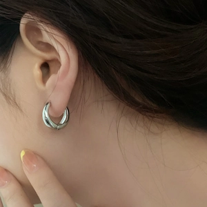 Close-up of minimalist silver hoop earrings worn to show scale and metallic luster