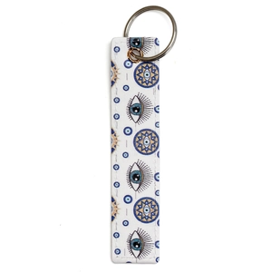 Close-up of a white faux leather keychain strap featuring a blue evil eye eyelash pattern