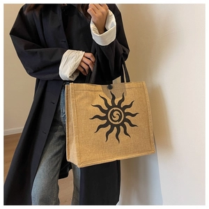 Street style shot of large khaki jute tote bag with black sunburst pattern detail